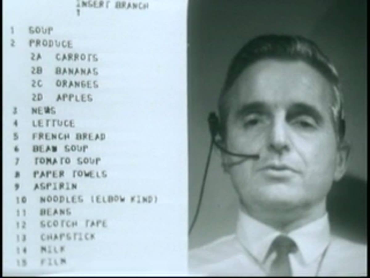 Engelbart, headset on, with an on-screen hierarchical list visible beside him.