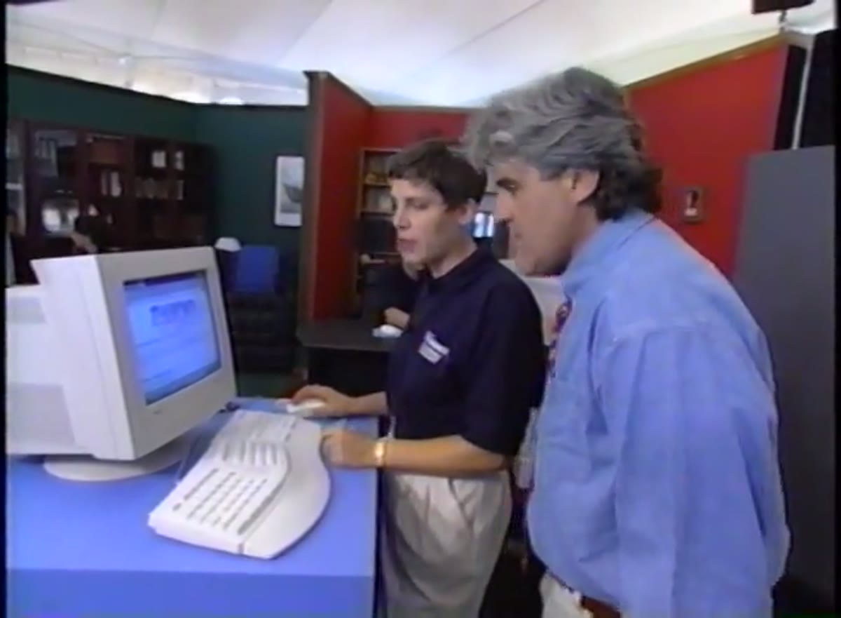 Bill Gates and Jay Leno standing at a computer workstation on stage.