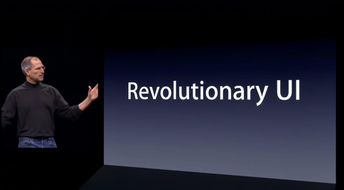 Steve Jobs on stage beside a screen reading Revolutionary UI.