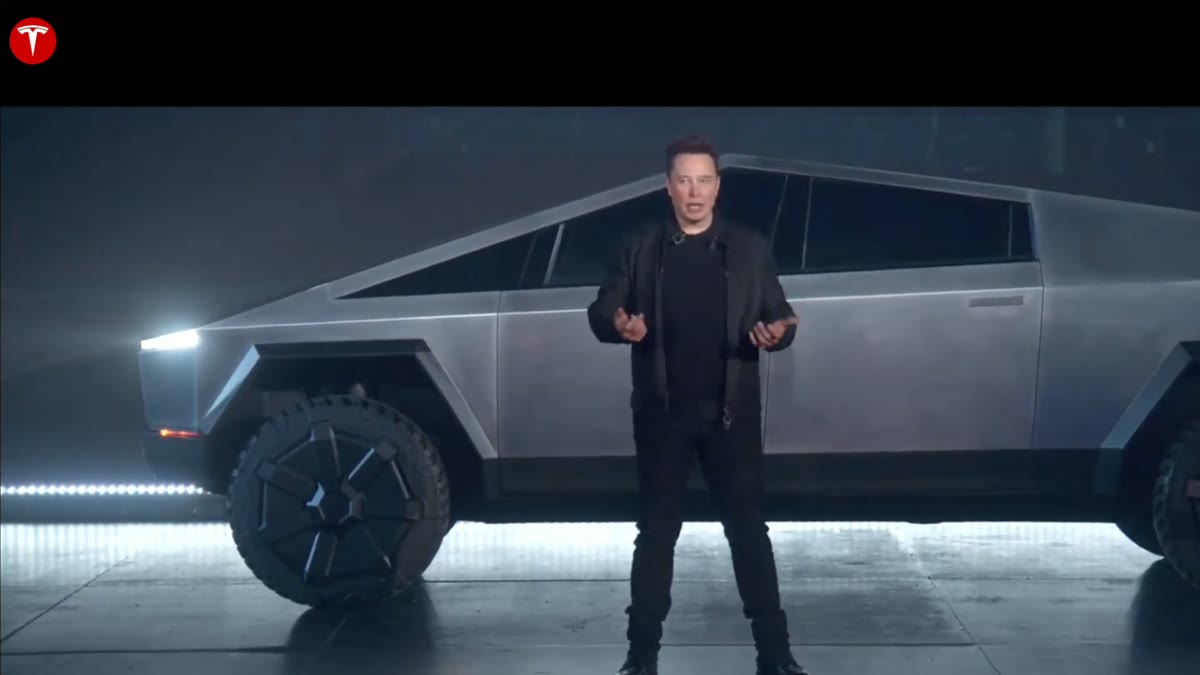 Elon Musk standing beside the newly unveiled Cybertruck on a dark stage.